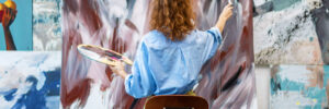 Woman artist is drawing on canvas with brush